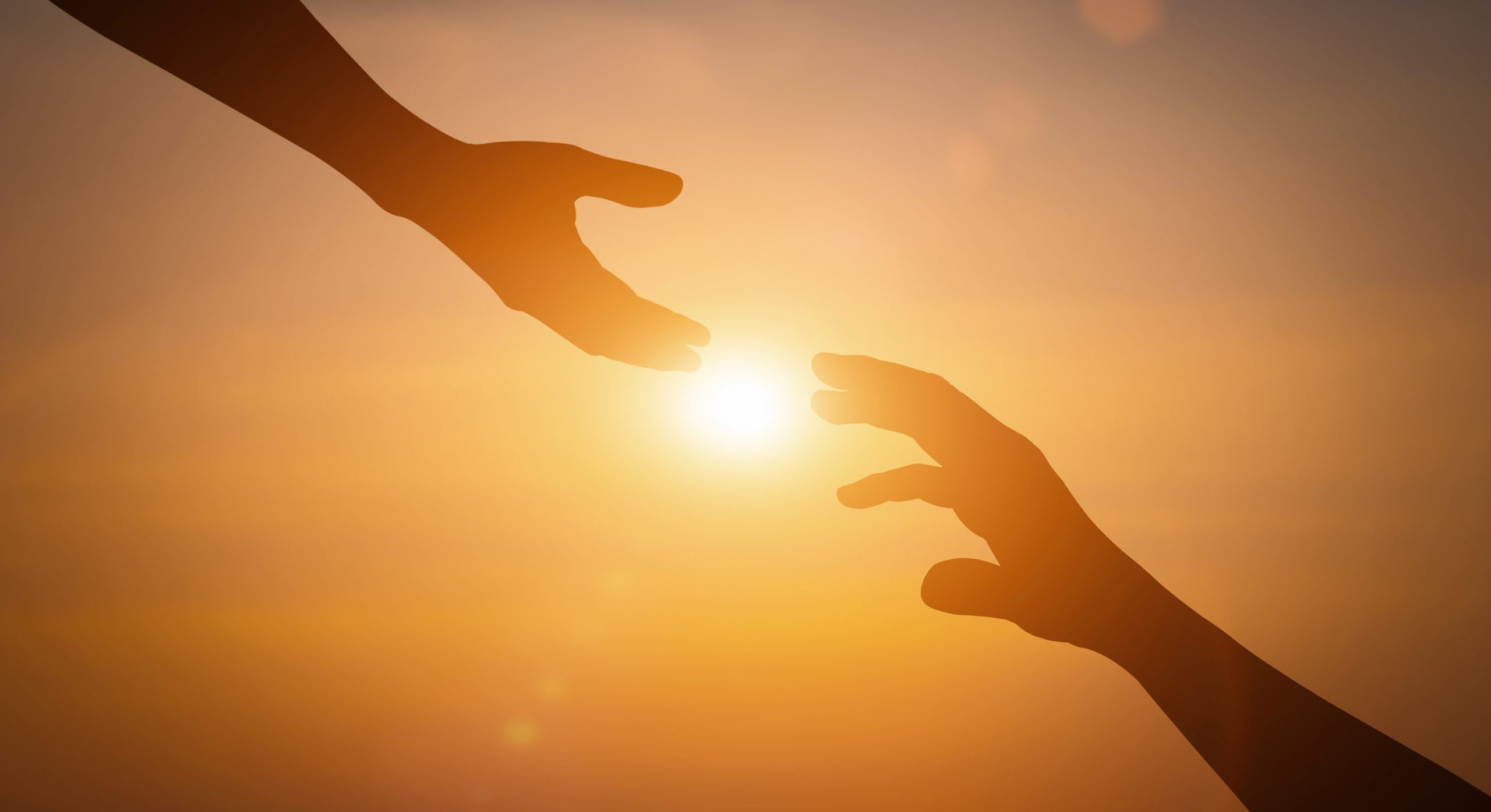 Silhouette of reaching, giving a helping hand, hope and support each other over sunset background.